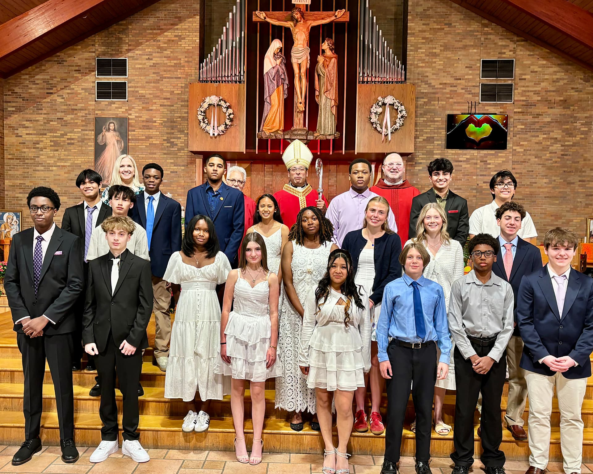 Students, families and clergy pose with a bishop in the sanctuary