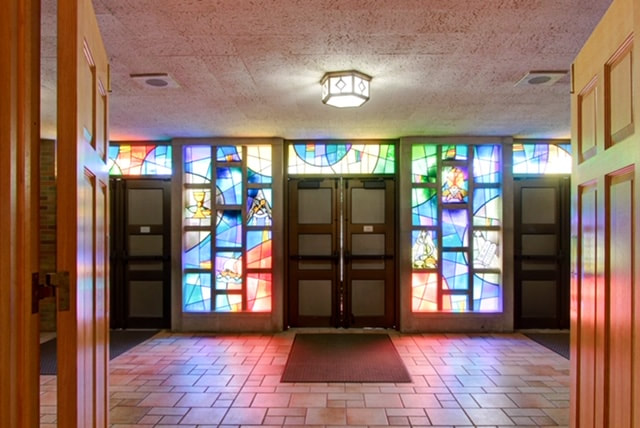 Vestibule with colored light streaming through stained glass doors